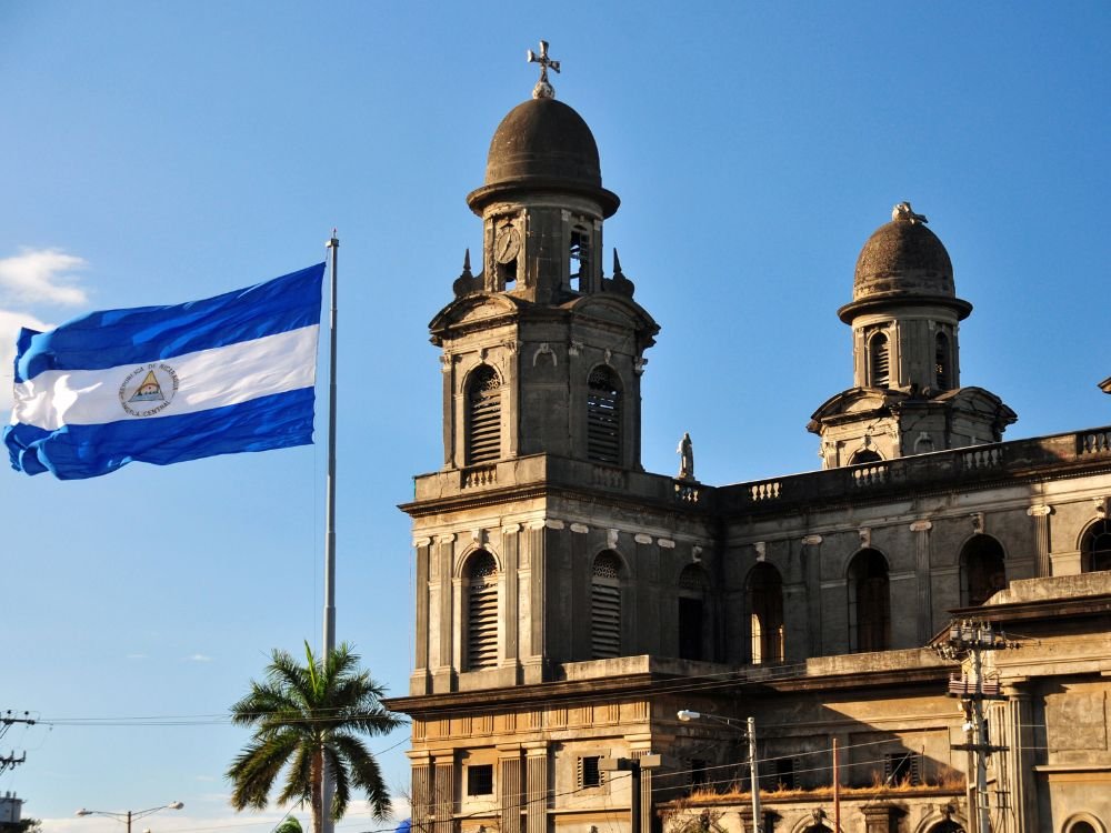 Nicaragua Immigration Visas, Residency & What Expats Need to Know Image of Nicaraguan flag and immigration building in Managua